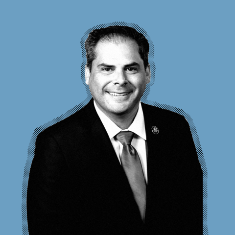 A black and white photo of Rep. Mike Garcia against a blue background.